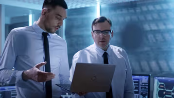 Two professionals reviewing a currency portal dashboard.