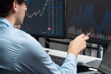 Trader reviewing market charts on multiple monitors.